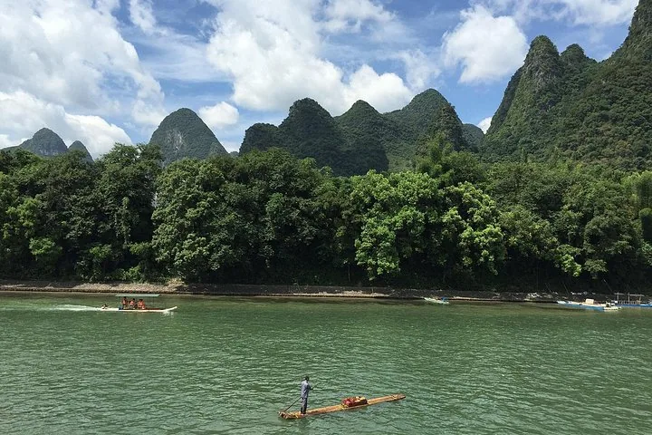 Person steering a traditional bamboo raft on the scenic Li River